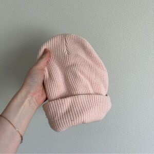 Baby pink knit beanie from garage with a couple snags